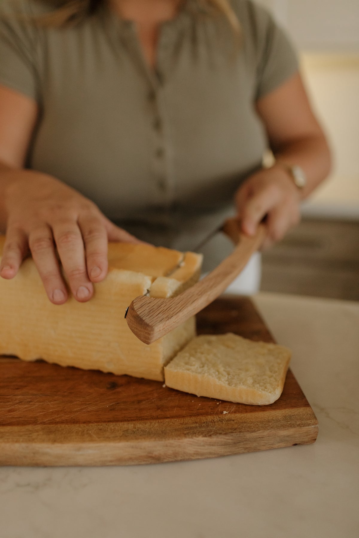 Hands slicing a loaf of homemade sourdough
