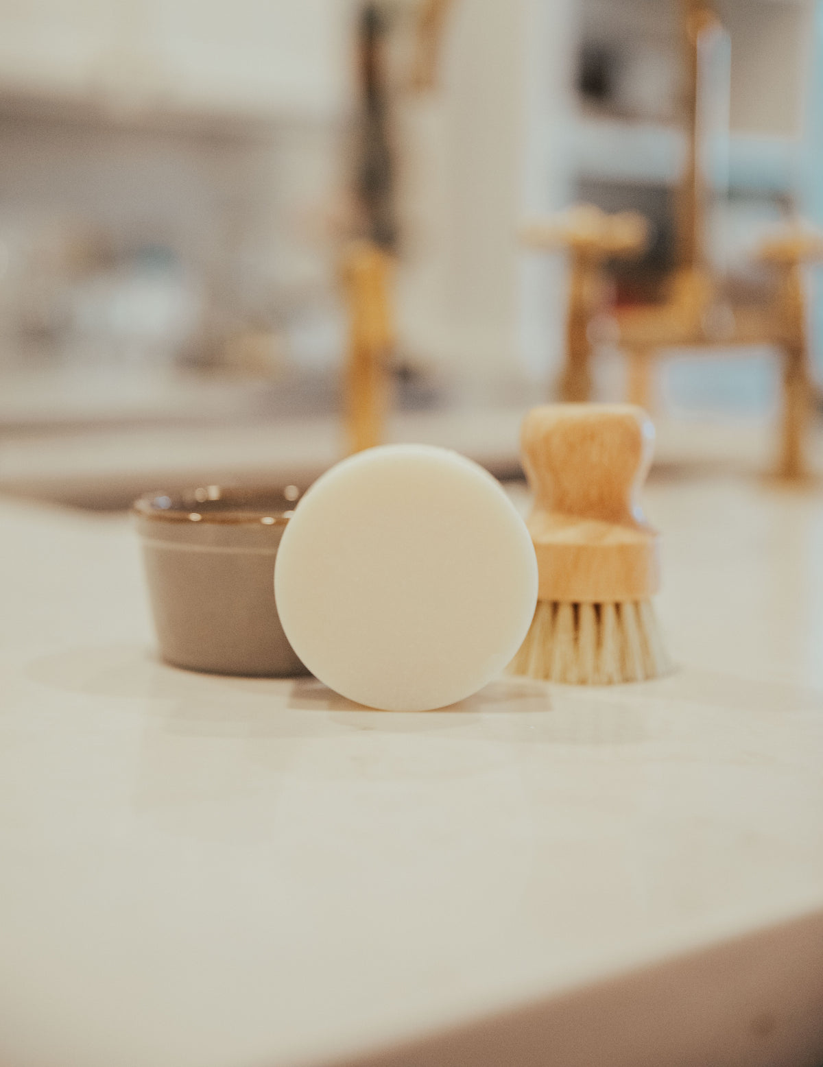 The Solid Dish Soap Set by a brass kitchen faucet
