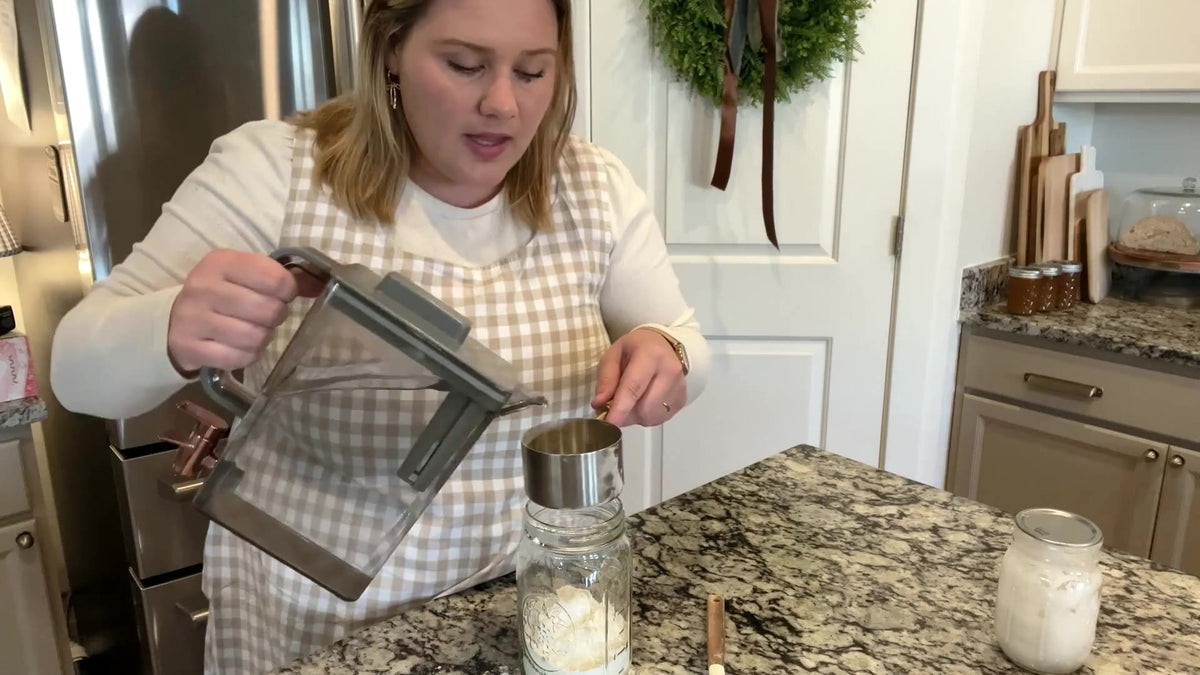Abbie Flake measuring flour into a mason jar at her kitchen counter